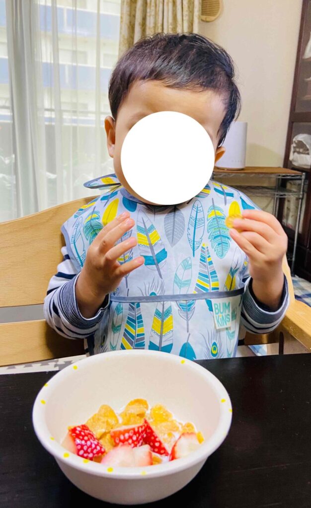 お食事エプロンを付けてフルーツを食べる子供