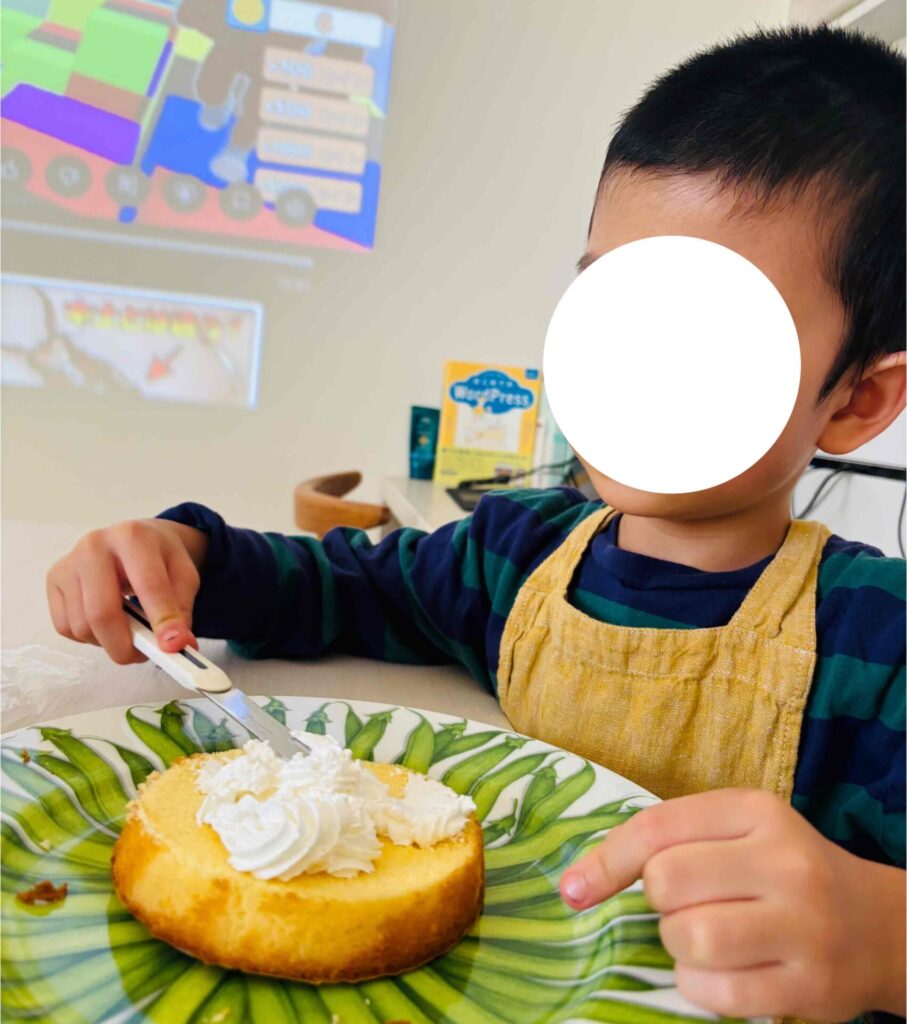 スポンジケーキにホイップを塗る子供