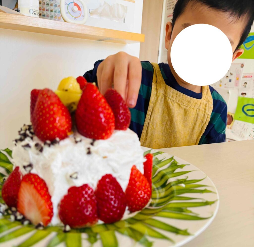 ケーキの上にイチゴを飾り付ける子供